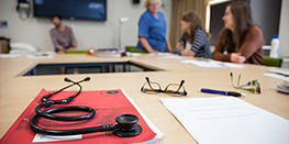 Stethoscope resting on a workbook during a tutorial