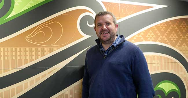 A man standing in front of a wall with a painted pattern on it