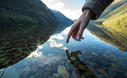 Hand reaching into a scenic river thumbnail