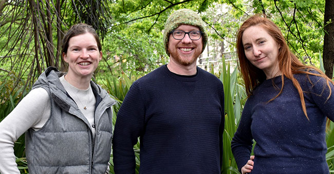 Three people standing in front of trees 