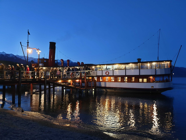 The TSS Earnslaw moored on the edge of Lake Wakatipu, unloading conference participants onto a wharf in the dusk.