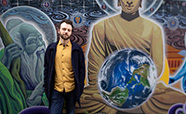 Joseph Watts standing in front of an outdoor wall mural