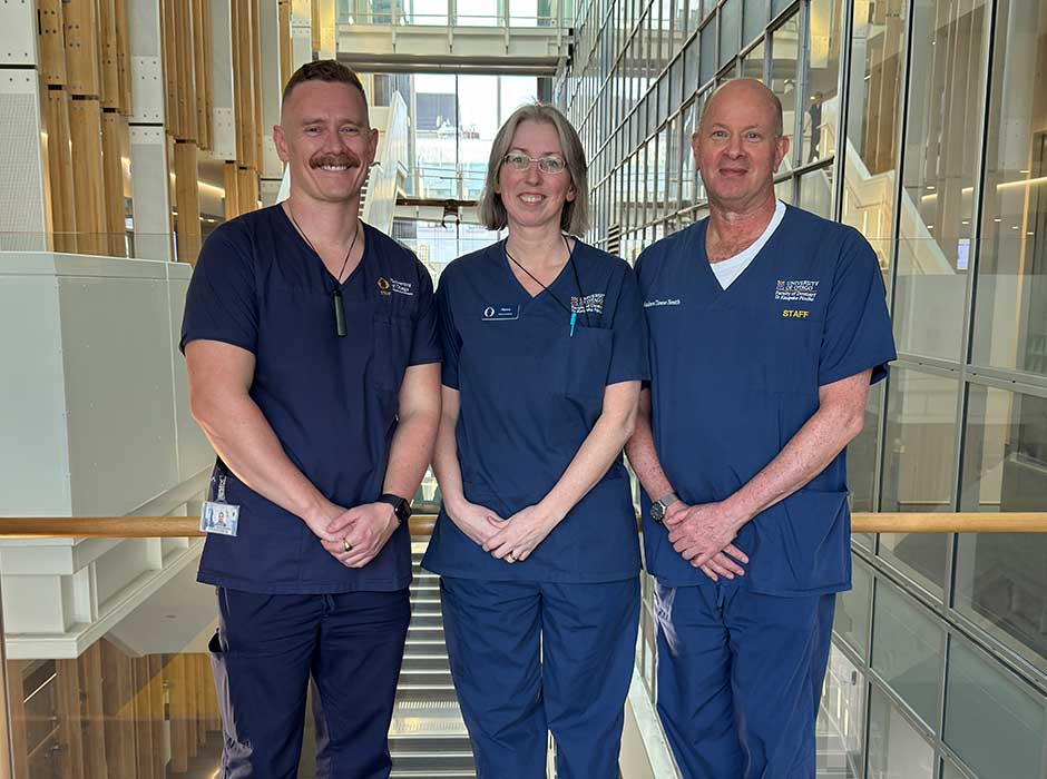 three people standing next to each other, all wearing blue scrubs