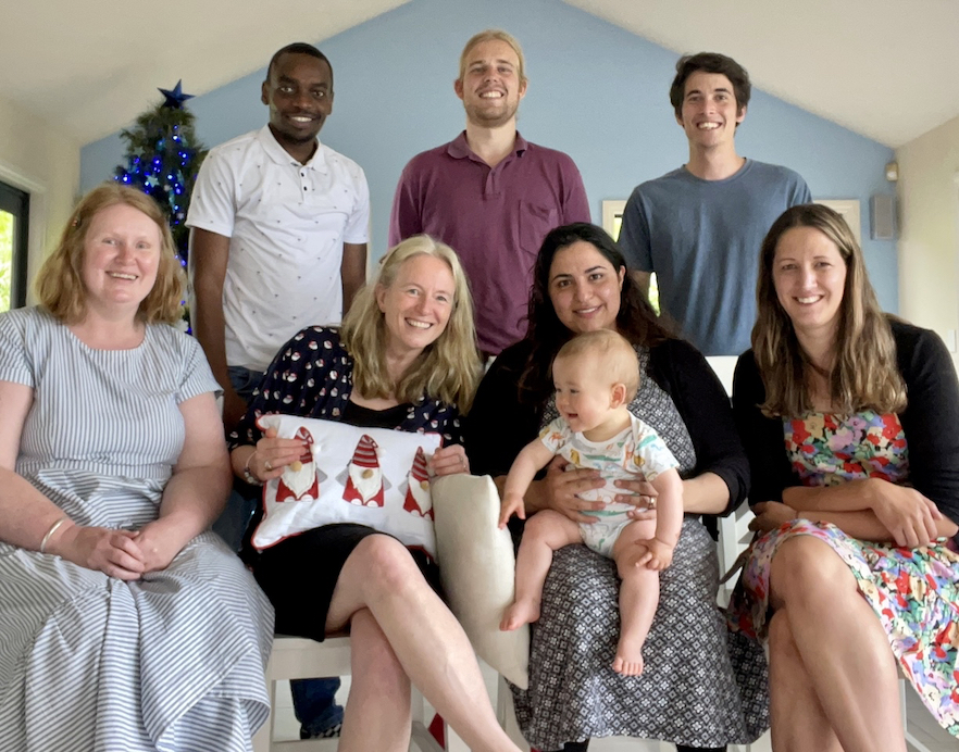 Epilepsy Research team members including a young baby gathered on and behind a couch in a home at Christmas 2022 image