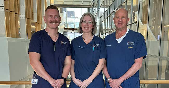 three people standing wearing blue scrubs
