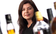 Professor Jennie Connor standing behind alcohol bottles