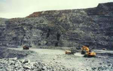 Macraes open-pit hard-rock gold mine near Dunedin. The mine extends deep into the unoxidised schist, following a gold-bearing zone which slopes gently northeastwards. Each bench is 10 metres high. The thin zone of oxidised schist can be seen at the top of the pit