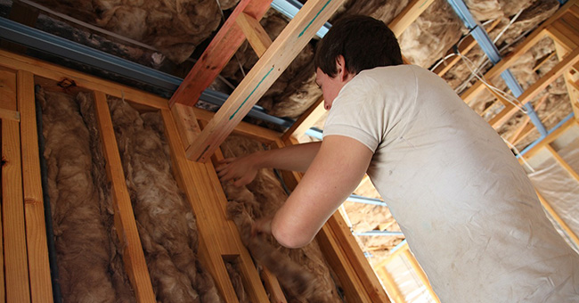 Stock image of a builder installing insulation in a partially-built house
