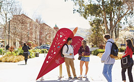 Students on campus by sculpture