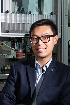 Dr Khoon Lim with 3D printer behind 226 news