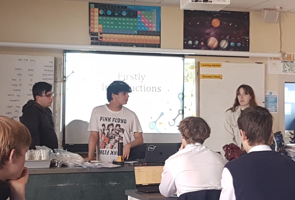 Three people presenting at the front of a classroom.