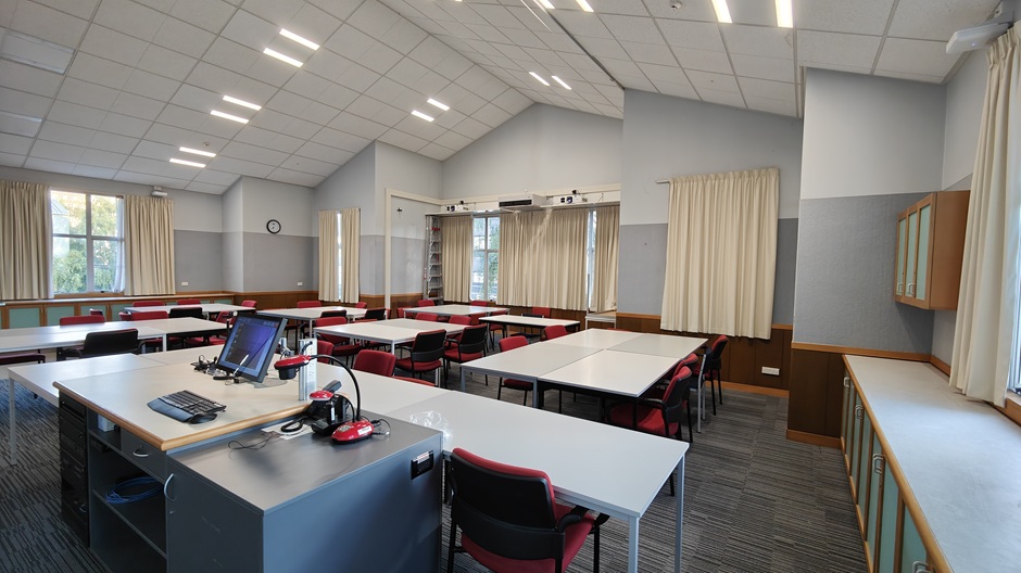 A view of Ōwheo building seminar room 206, showing tables and chairs in groups
