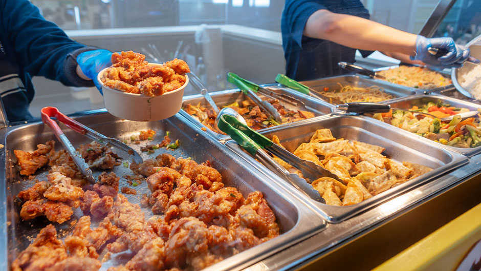 A close-up of staff serving takeaway food from a chinese buffet