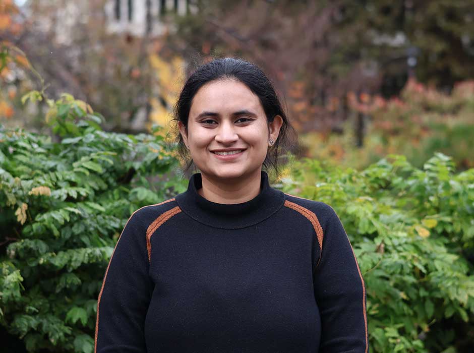 A woman standing in front of greenery