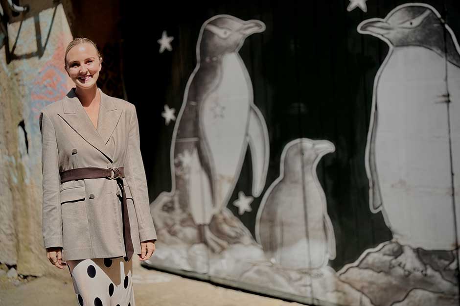 A woman standing in front of a black wall with penguins painted on it