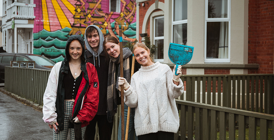 group of students posing with brooms during street clean-up 