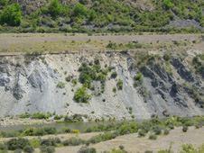 Soft fault gouge zone on a branch of the Blue Lake Fault at Fiddlers Flat. The gouge zone separates well-bedded greywacke and argillite (dark, right) from highly sheared broken formation (photo below). The pale gouge rocks on the left are mainly finely ground argillite with abundant calcium carbonate cement and veins.