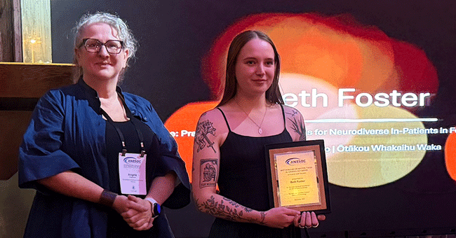 Two woman standing, one holding a certificate 