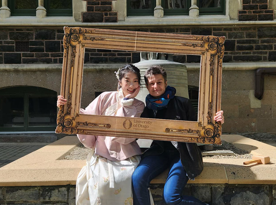 Two women posing for a photo holding a large cutout of a photo frame