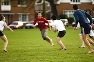 Photo of young men playing a social game of rugby in a park 