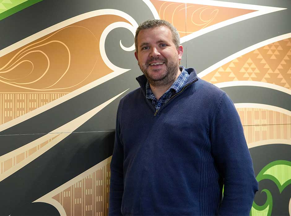 A man standing in front of a wall with a pattern painted on it