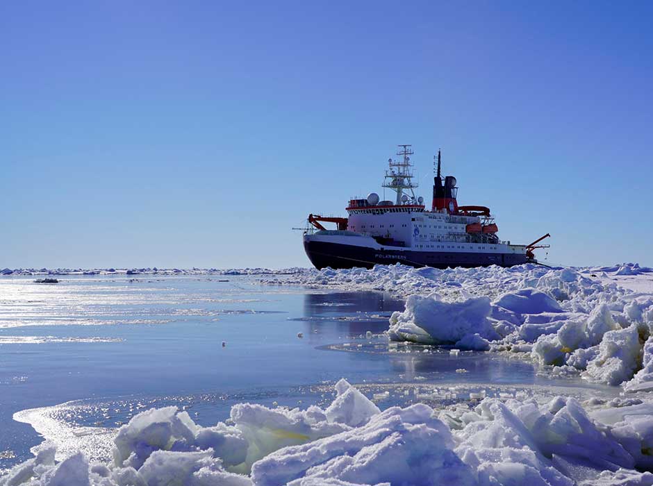 a ship travelling through icy water on a sunny day