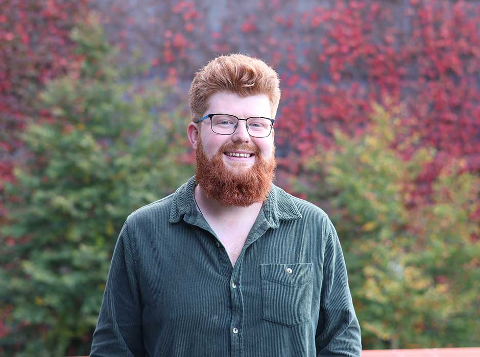 A man standing in front of greenery