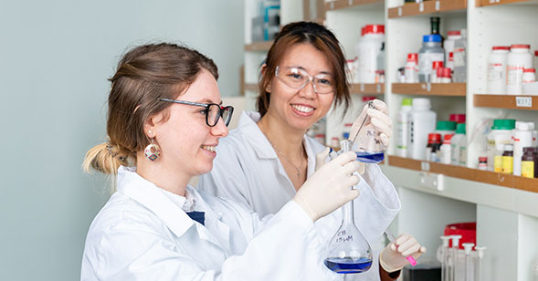 Pharmacology students in lab, one holds a test tube.