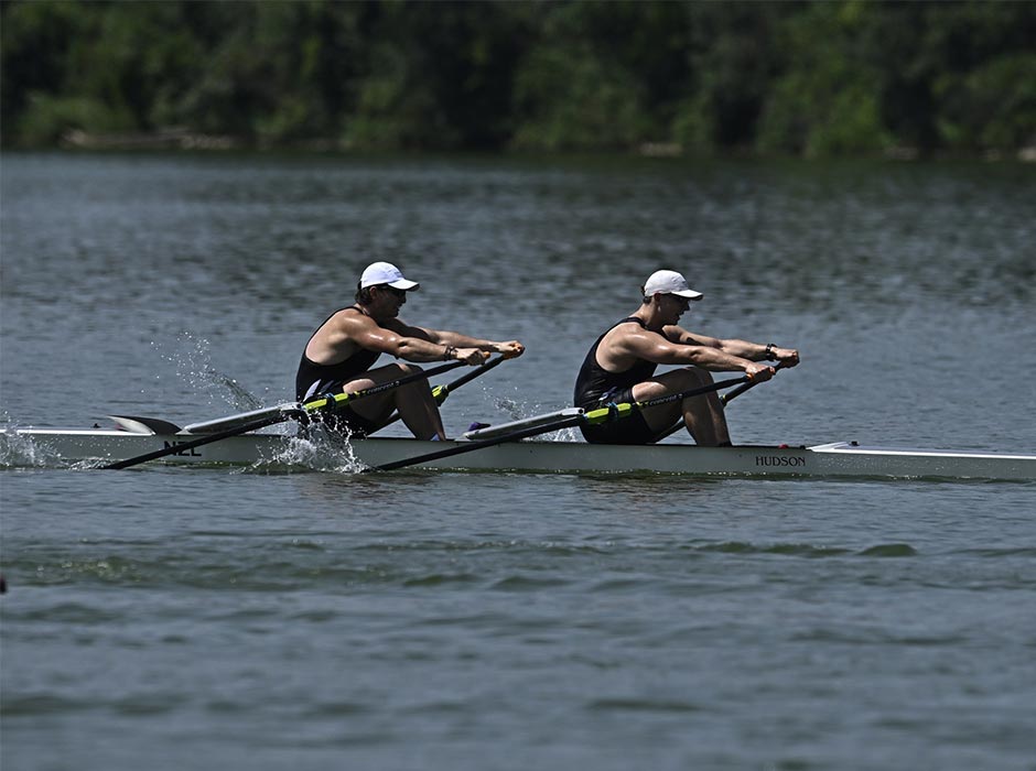 Two men row out on the water.