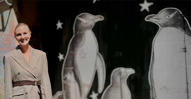 A woman standing in front of a black wall with penguins painted on it
