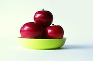 Photo of 3 red apples in a green bowl