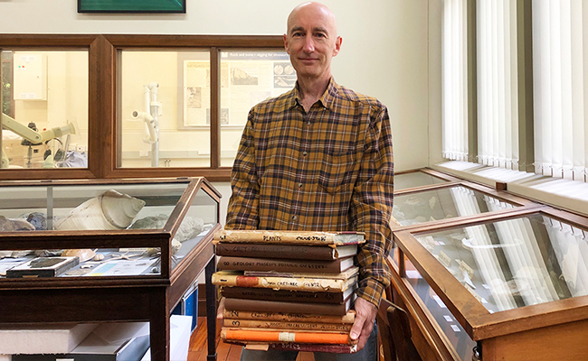 Dr Robinson holds a collection of historic catalogues used to record details of fossils collected for research and teaching