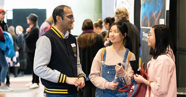 Two young people speaking with a University staff member on Tertiary Open Day