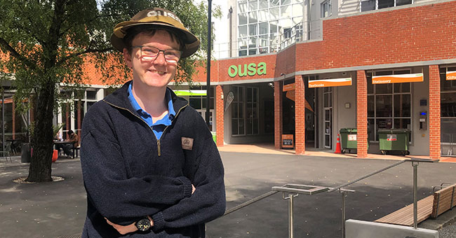 A man standing in front of a building with the OUSA logo on it