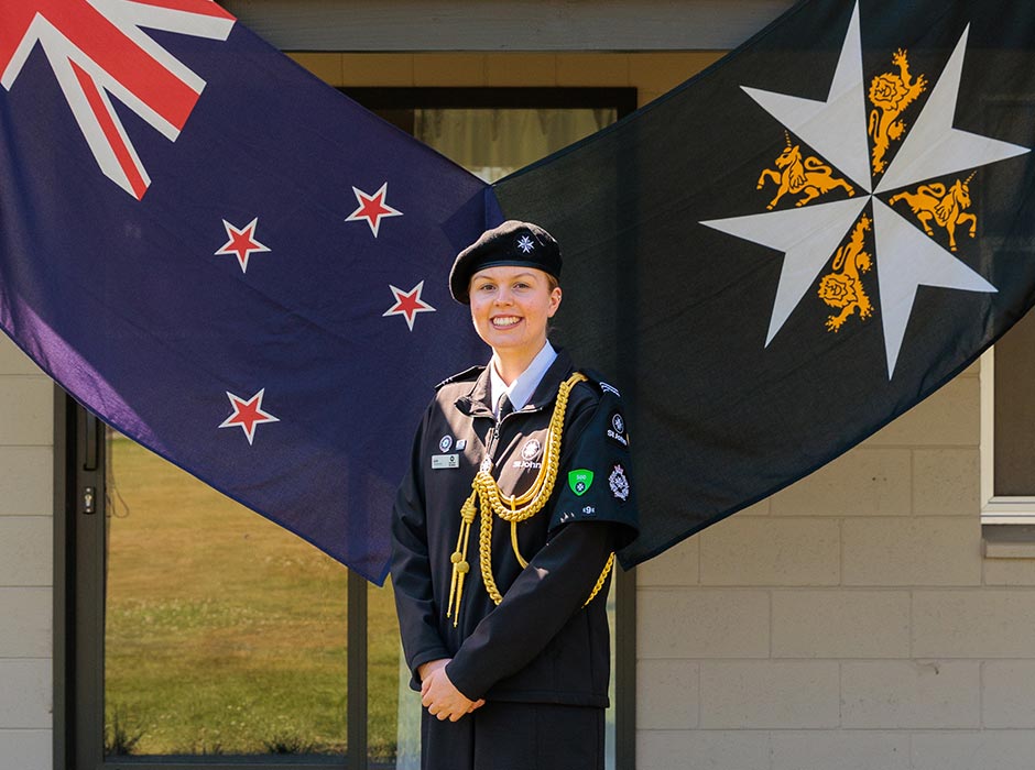 A woman in uniform standing in front og two flags