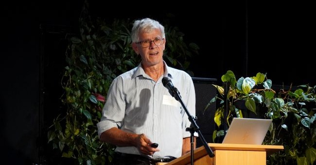A man addresses an audience from a podium