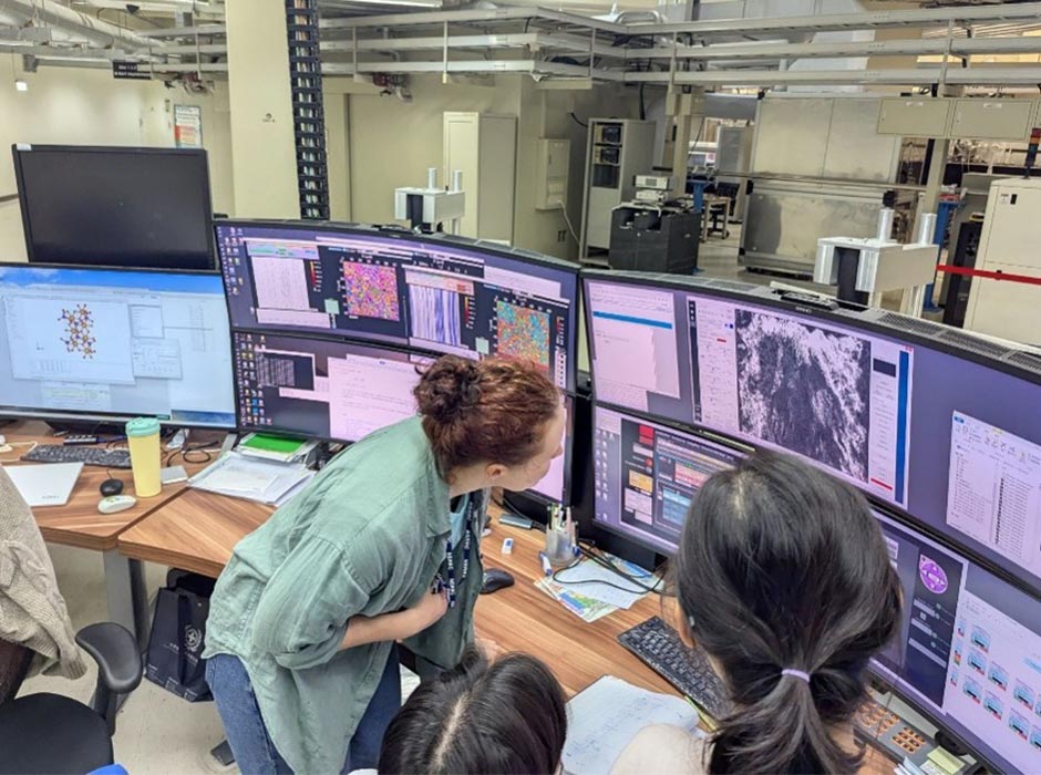Three people look at computers in a lab setting.