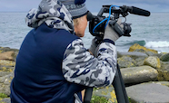 Videographer filming a rocky shore