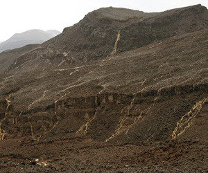 Desert storm! After a sudden deluge with hail and thunder, the Harrat Rahat Volcanic Field, here showing an eroded cone, sprang to life with rivulets and lakes.