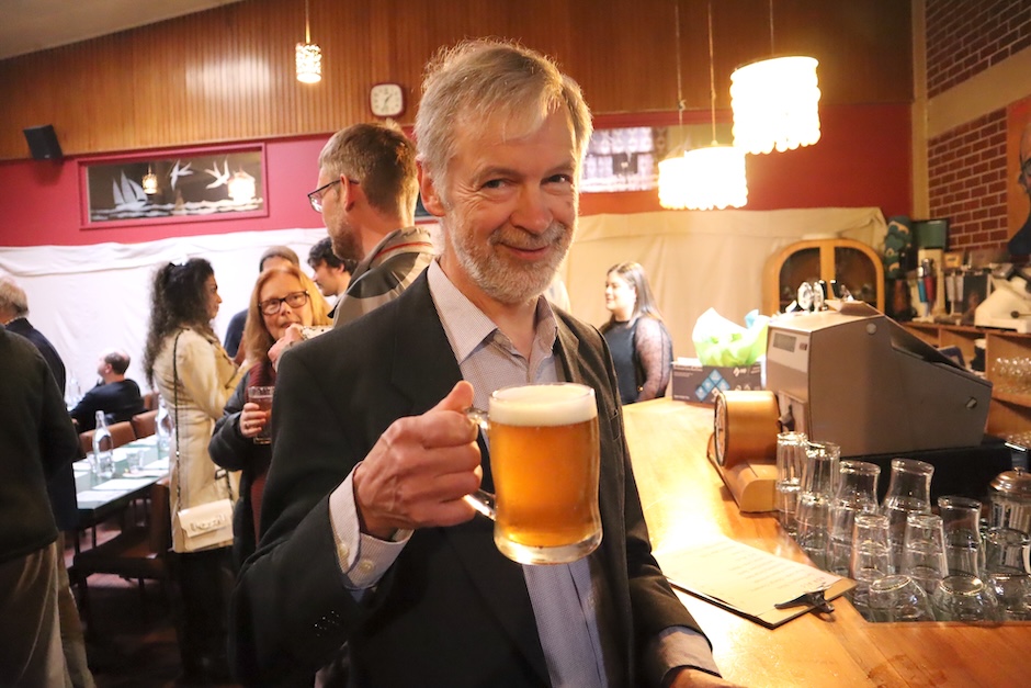 Ian Lamont raising a glass of beer at farewell event.