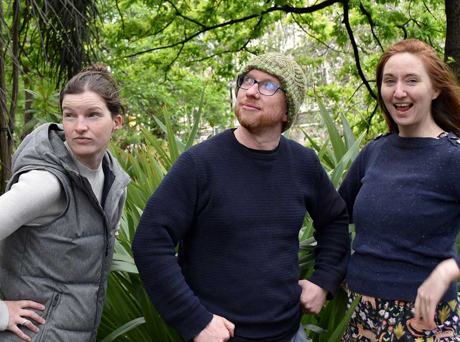 Three people standing in front of trees
