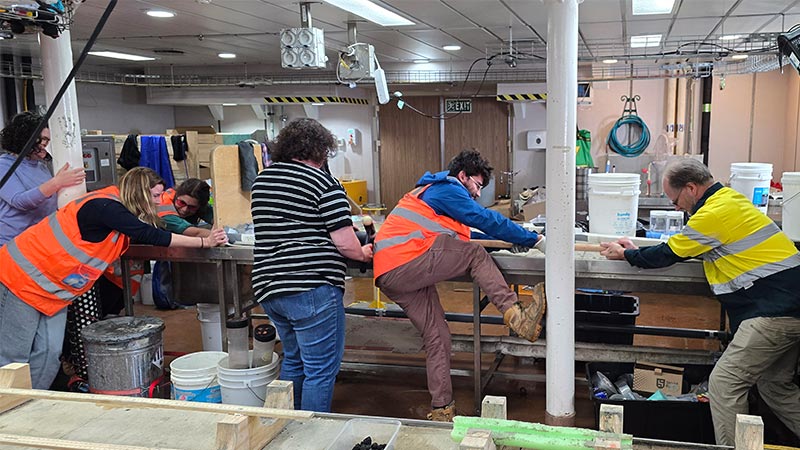 Researchers removing a core on a research vessel 