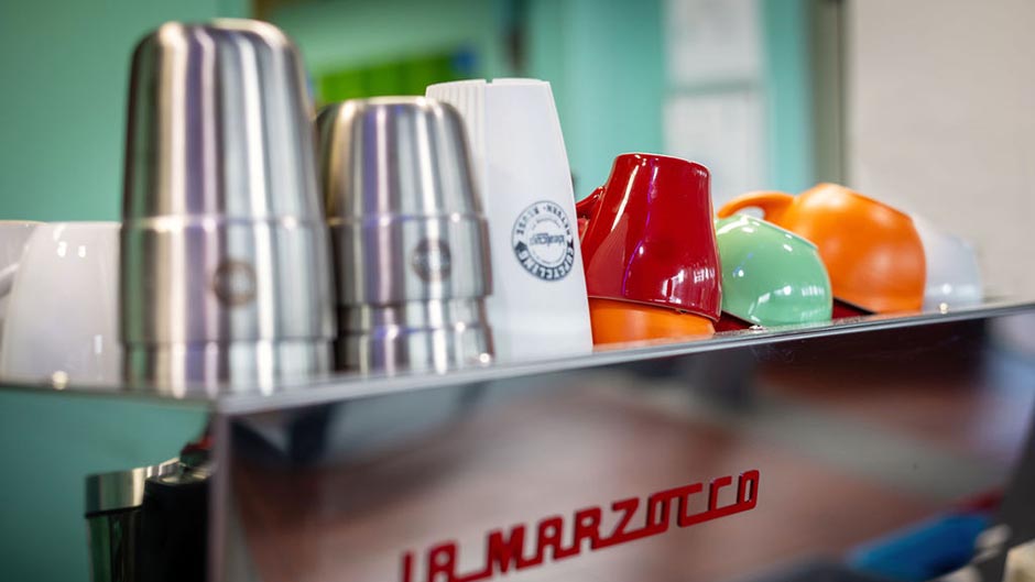 Returnable takeaway cups and ceramic coffee cups on top of the Cafe Albany coffee machine