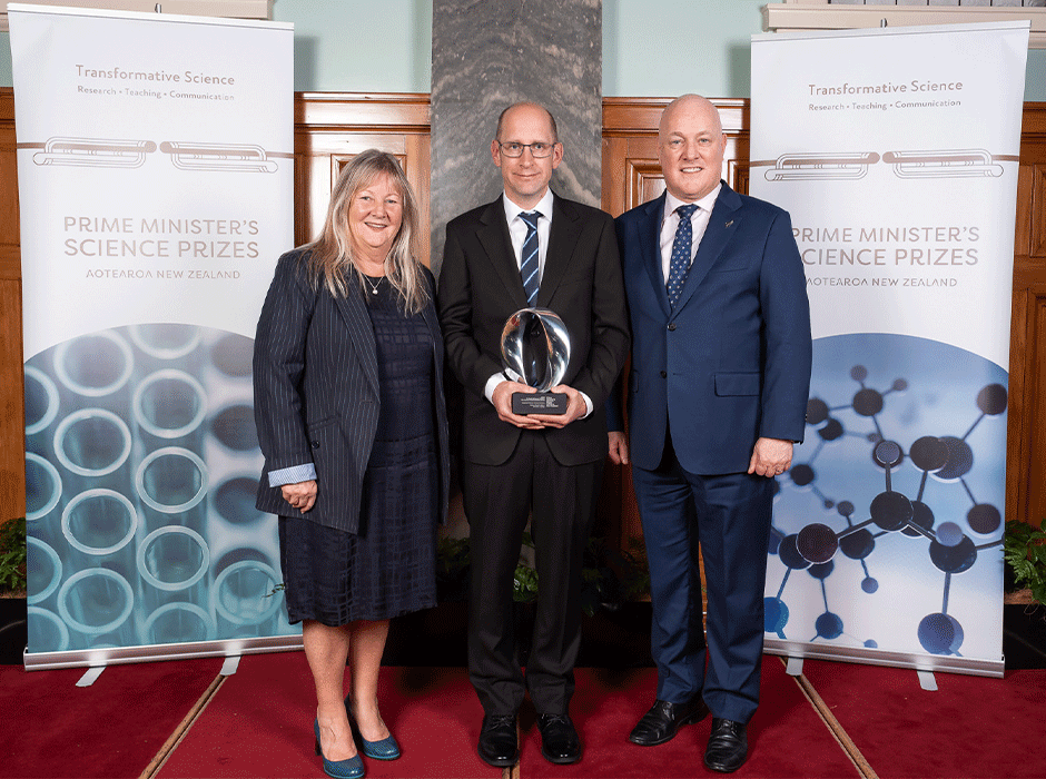 three people, one holding an award