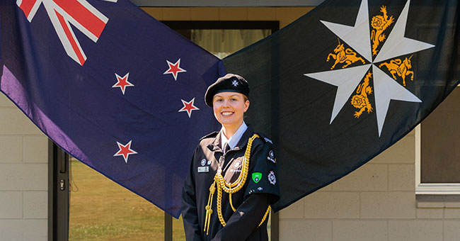 A woman in uniform standing in front og two flags