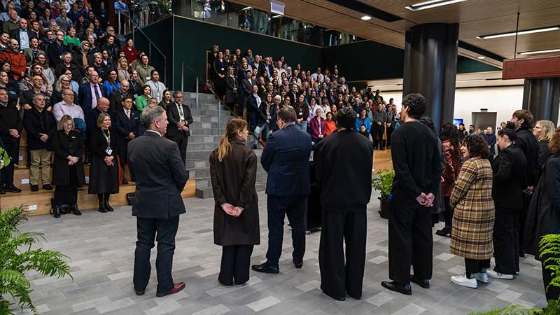 A handful of people standing with their backs to the camera addressing an auditorium full of people