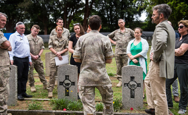 Group of army personnel and forensic experts gathered in a cemetery
