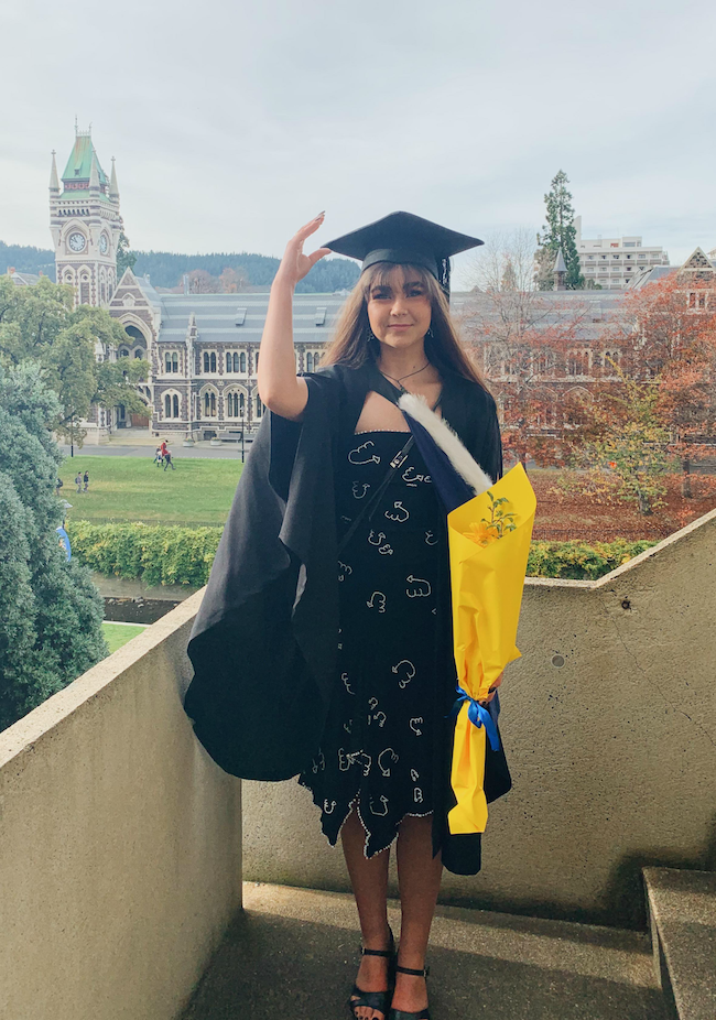 Emma Muir standing outside the clocktower in her graduation gown and black and white embroidered dress