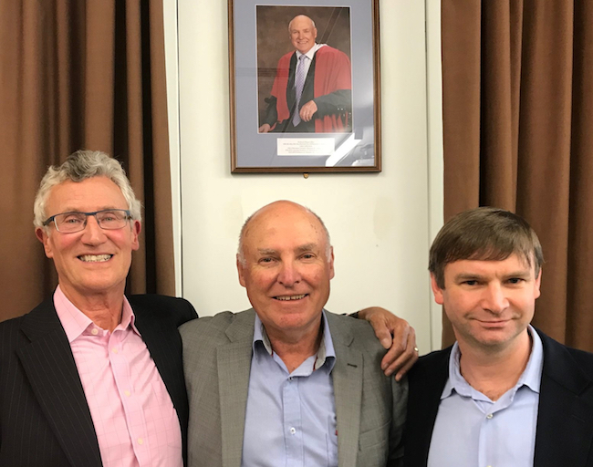 Wayne Gillett with colleagues below the photo