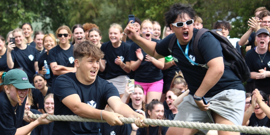 Students competing in a tug of war, yanking on a thick rope. Go team!